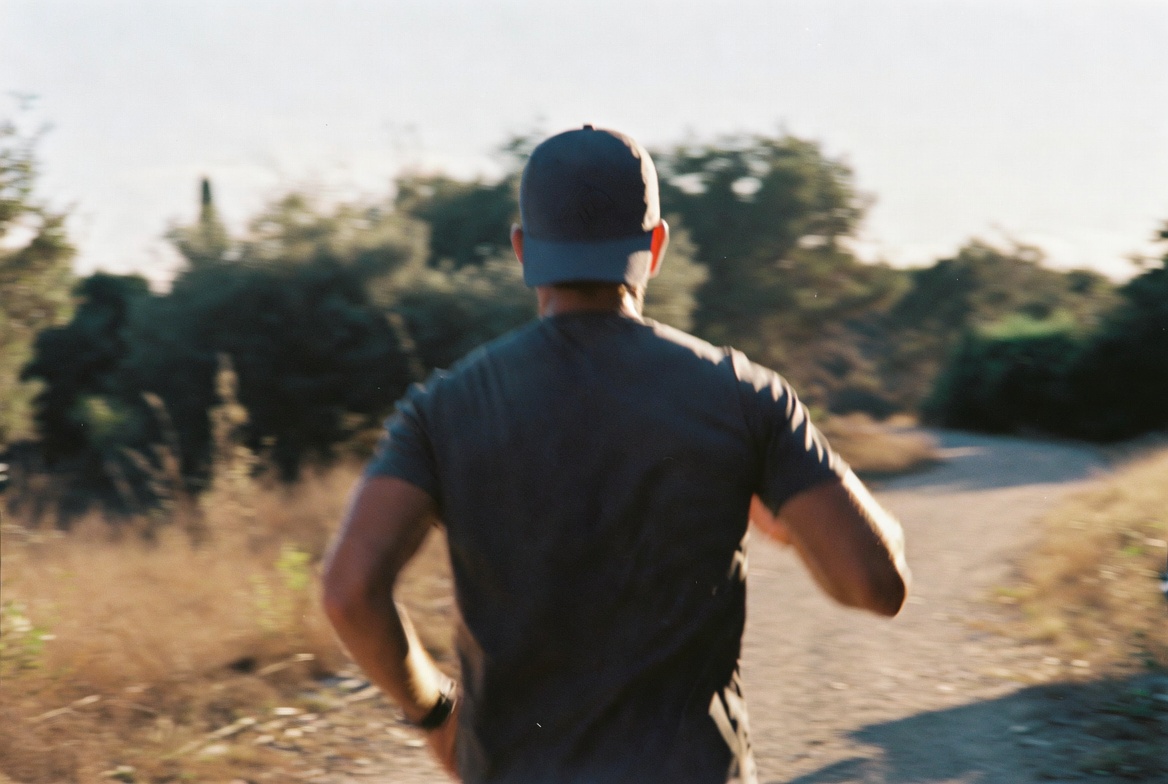 Runner wearing a lightweight cap on a trail at sunrise